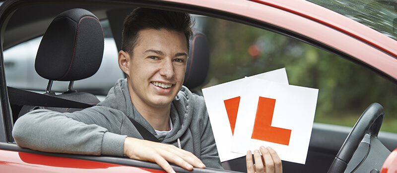 boy holding l plates in car