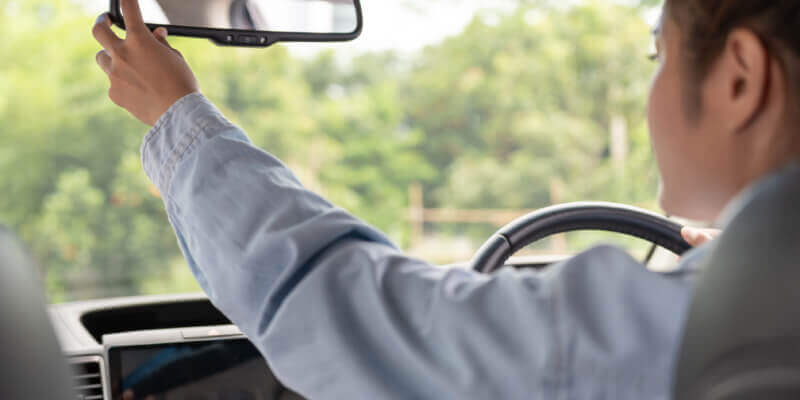 Girl reaching to adjust rear view mirror