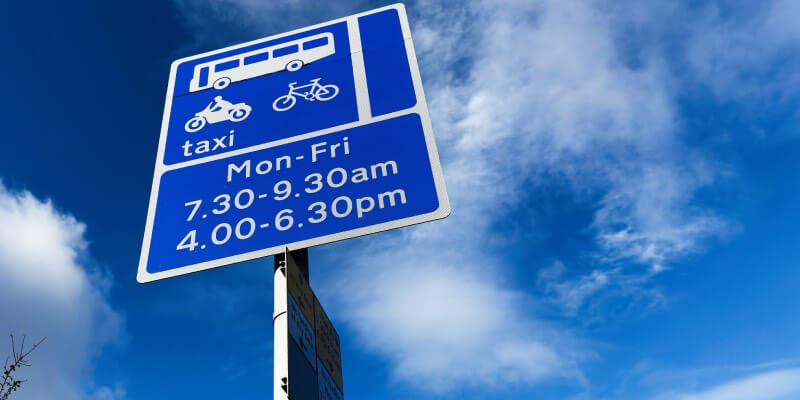 Blue sign showing times for bus lane restrictions